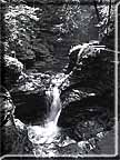 Black and white photograph of a series of small waterfalls in upper Buttermilk Falls gorge.