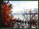 A photo taken of a dock in autumn on Cayuga Lake with Ithaca, New York in the distance.