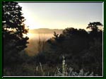 Photo of the sun rising over a misty valley.