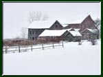 Snow floating down over old farm buildings.