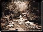 A sepia print showing a distant waterfall with sunlight in the distance.